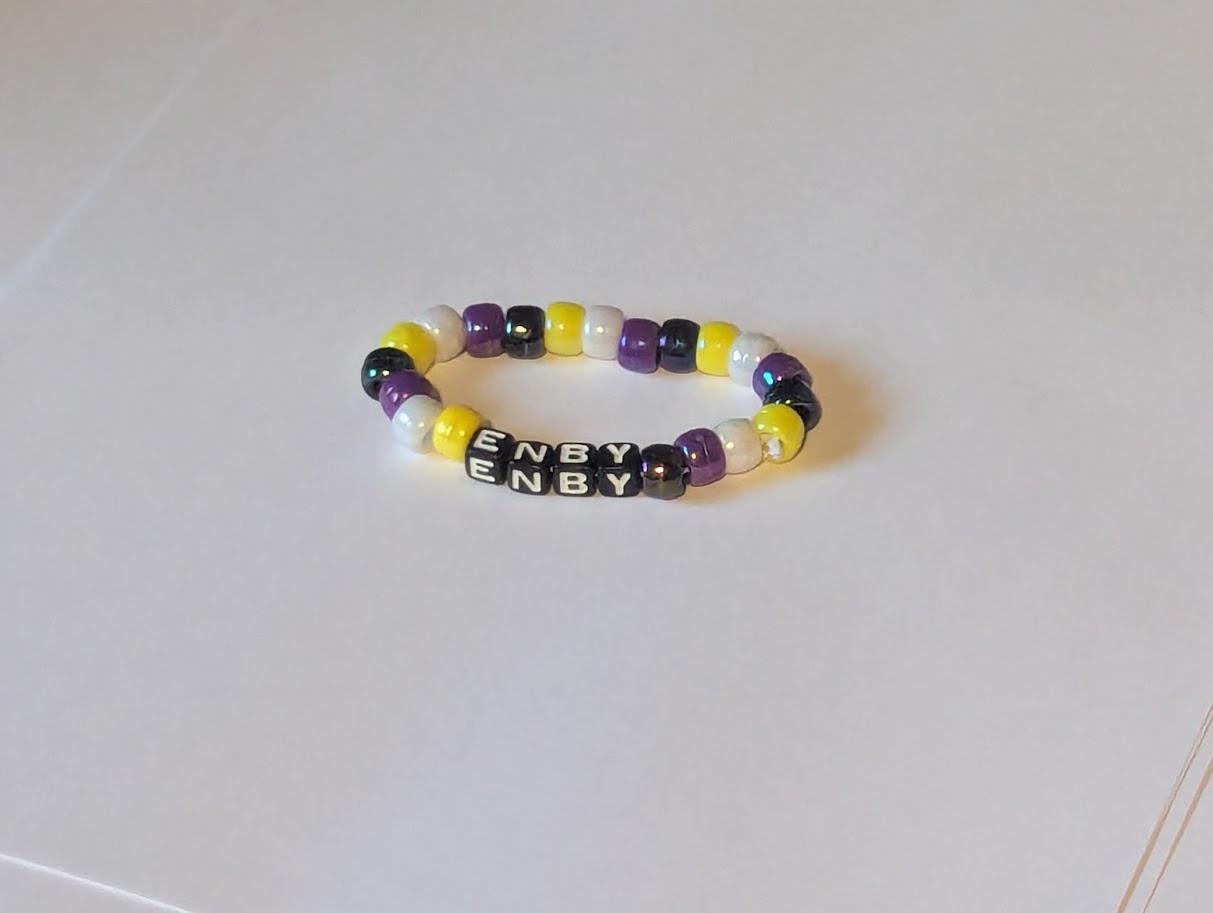 Nonbinary flag color bracelet with the word Enby on it